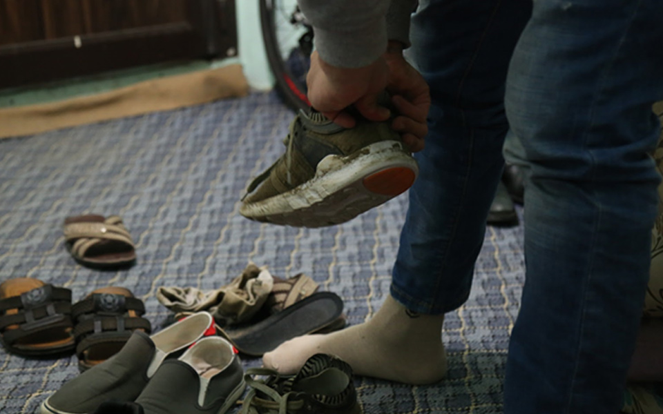 Güvenli evde bir göçmen ‘oyun’dan önce ayakkabılarına yeni tabanlık yerleştiriyor. (Foto: Andrew Seal)